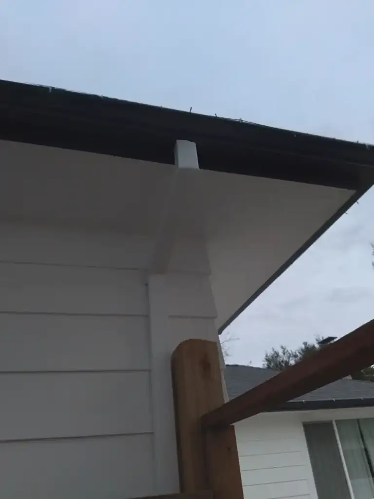 New white downspout coming off the gutter at the corner of a house