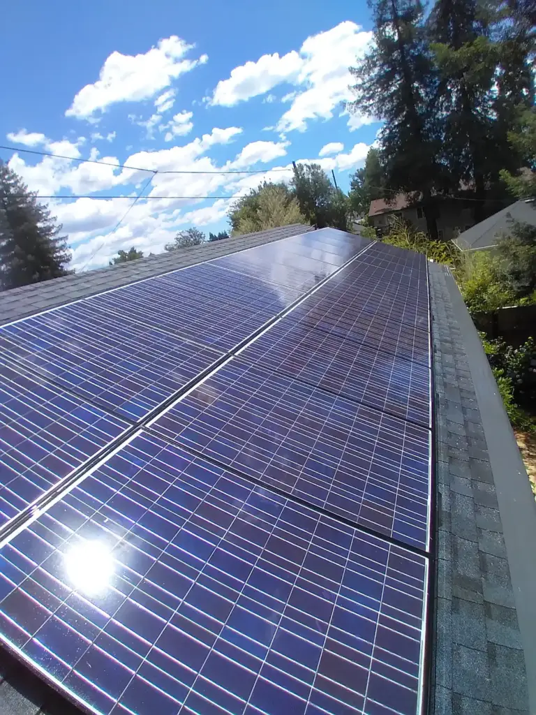 Rooftop solar panels catching the sun along a shingle roof